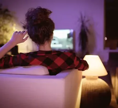 Viewer relaxing on the couch watching TV at night