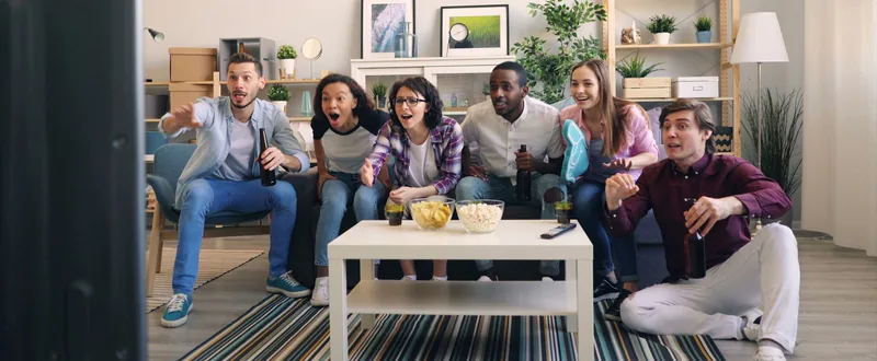 Friends on a couch reacting to a live game on TV